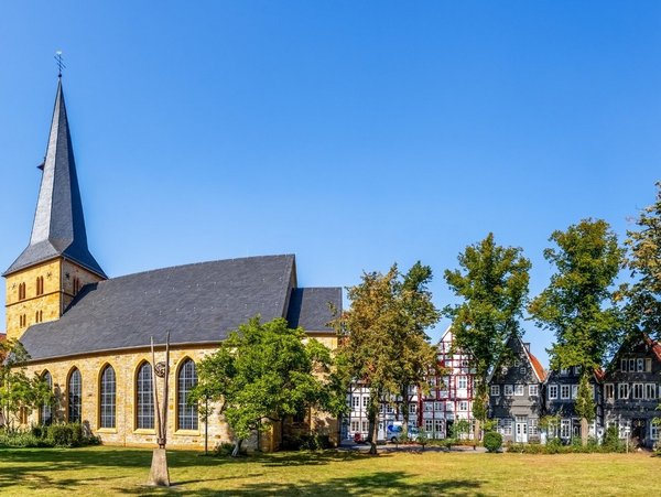 Kirche mit Fachwerkhäusern und Parkanlage in Gütersloh bei blauem Himmel