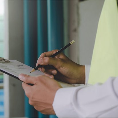 Qualitätsmanagement bei TÜV NORD-KURS – zertifiziert und kundenorientiert Person mit Klemmbrett beim Ausfüllen eines Formulars zur Qualitätskontrolle