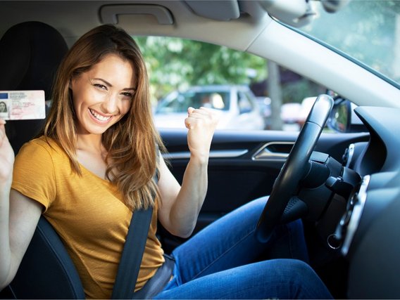 Zurück am Steuer mit dem MPU-Infocheck Glückliche Frau im Auto zeigt ihren Führerschein