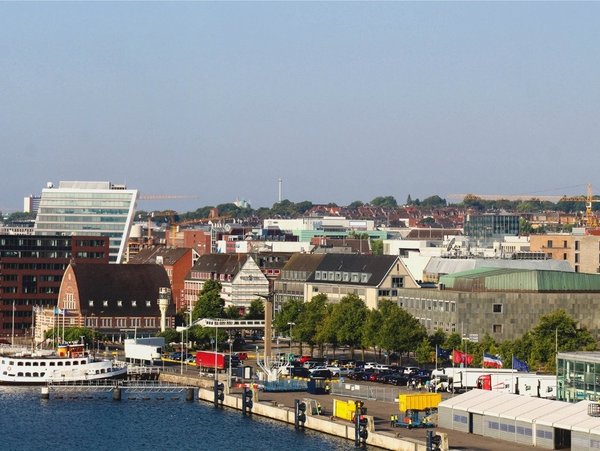 Blick auf den Kieler Hafen mit Kreuzfahrtschiff und Stadtpanorama