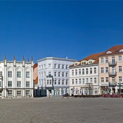 Historischer Marktplatz in Greifswald mit bunten Giebelhäusern bei blauem Himmel