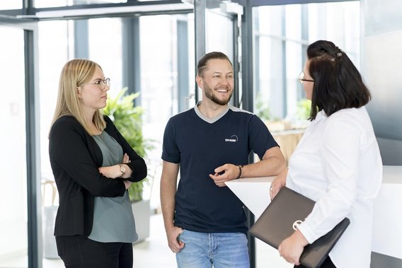 Drei Mitarbeitende von TÜV NORD-KURS im Gespräch im Eingangsbereich