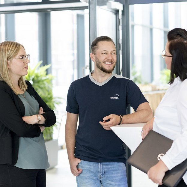 Drei Mitarbeitende von TÜV NORD-KURS im Gespräch im Eingangsbereich