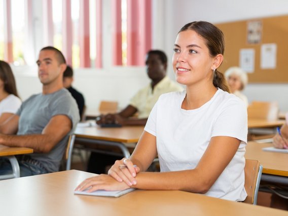 Junge Erwachsene sitzen aufmerksam im Seminarraum und hören einer Schulung zu