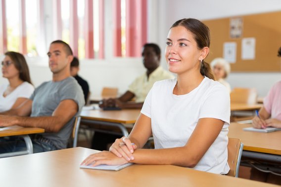 Junge Erwachsene sitzen aufmerksam im Seminarraum und hören einer Schulung zu