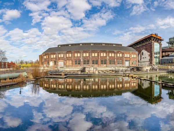 Historische Industriebauten am Wasser im Westpark Bochum mit reflektierendem Himmel im Teich