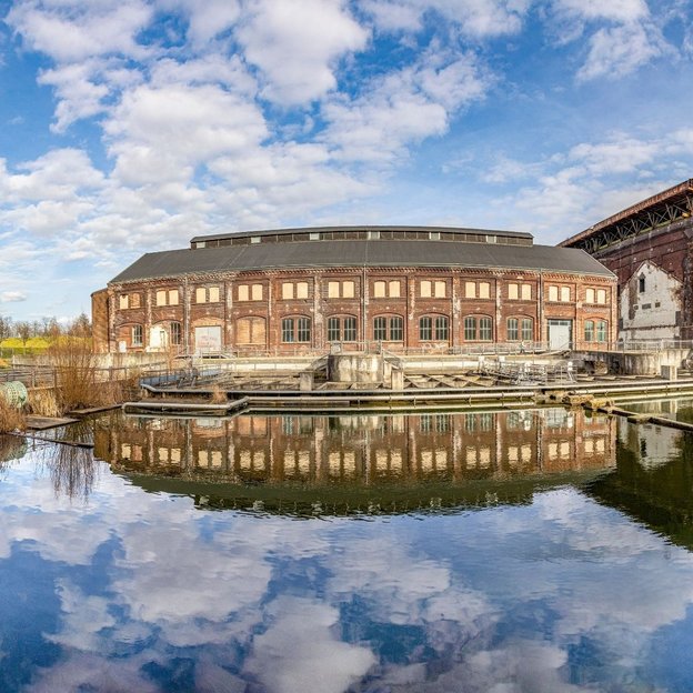 Historische Industriebauten am Wasser im Westpark Bochum mit reflektierendem Himmel im Teich