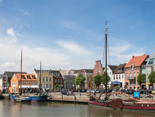 Blick auf den Hafen und die Altstadt von Husum mit Booten und bunten Häusern bei Tageslicht