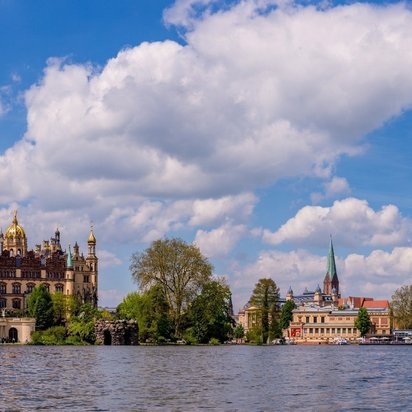 Schlossblick in Schwerin – Ihr Weg zur MPU-Vorbereitung bei TÜV NORD-KURS Blick auf das Schweriner Schloss am See bei blauem Himmel mit Wolken