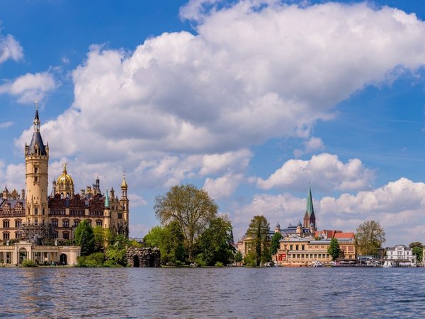 Blick auf das Schweriner Schloss am See bei blauem Himmel mit Wolken
