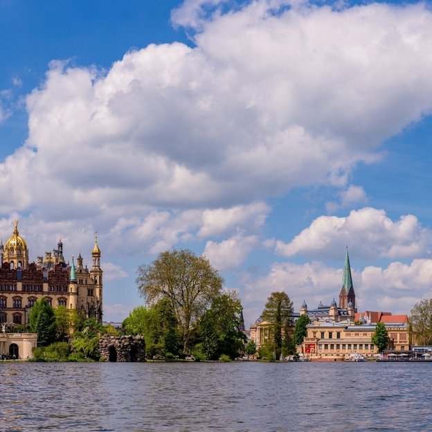 Blick auf das Schweriner Schloss am See bei blauem Himmel mit Wolken