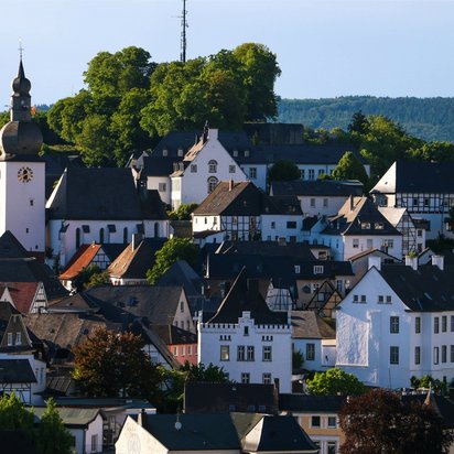 Historische Altstadt von Arnsberg im Sauerland. Blick auf die Altstadt von Arnsberg mit Kirche, Fachwerkhäusern und bewaldetem Hügel im Hintergrund.
