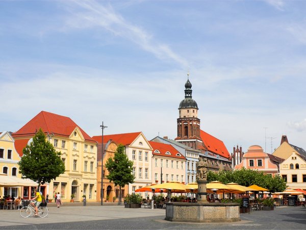 Historischer Marktplatz in Cottbus mit Springbrunnen, bunten Häusern und Kirchturm im Hintergrund