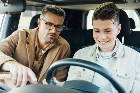 Junger Fahranfänger mit Begleitperson bei einer Fahrstunde im Auto