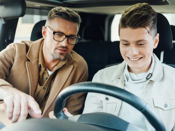 Junger Fahranfänger mit Begleitperson bei einer Fahrstunde im Auto